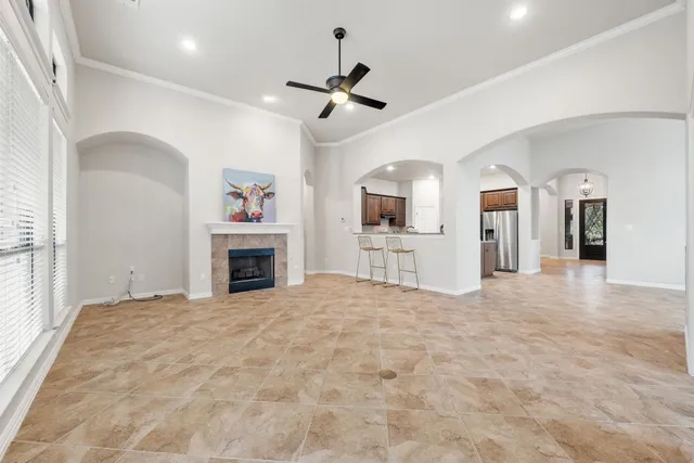 a view of a livingroom with a fireplace a sink a fireplace a ceiling fan and wooden floor