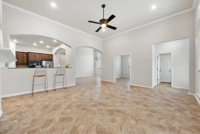 a view of a livingroom with a ceiling fan & kitchen view