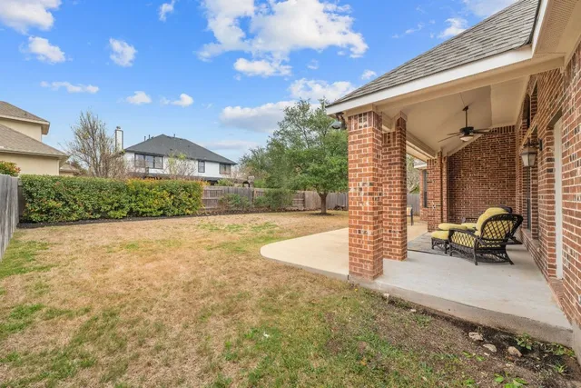 a view of a patio with couches and table and chairs with wooden fence and plants