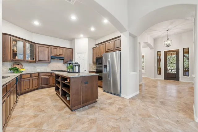 a kitchen with stainless steel appliances granite countertop a stove refrigerator and a sink