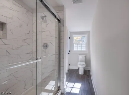 a bathroom with a granite countertop toilet a sink and shower