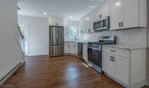 a kitchen with stainless steel appliances granite countertop a refrigerator stove and white cabinets