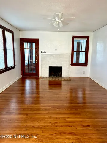 a view of an empty room with wooden floor and a fireplace