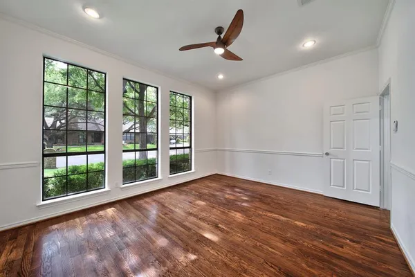 a view of an empty room with a window and wooden floor