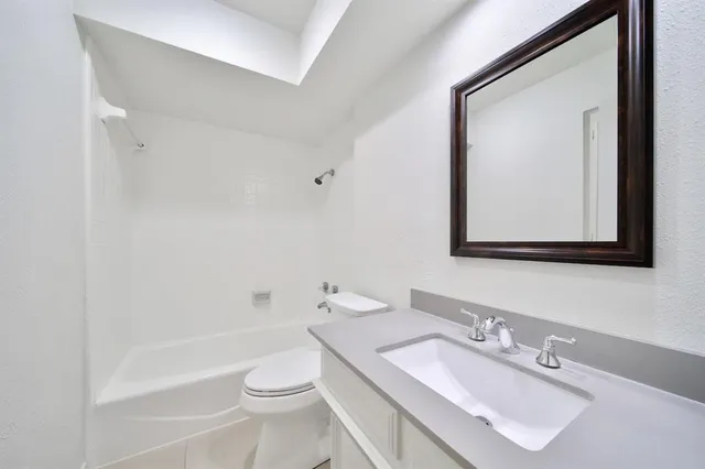 a bathroom with a granite countertop toilet sink and mirror