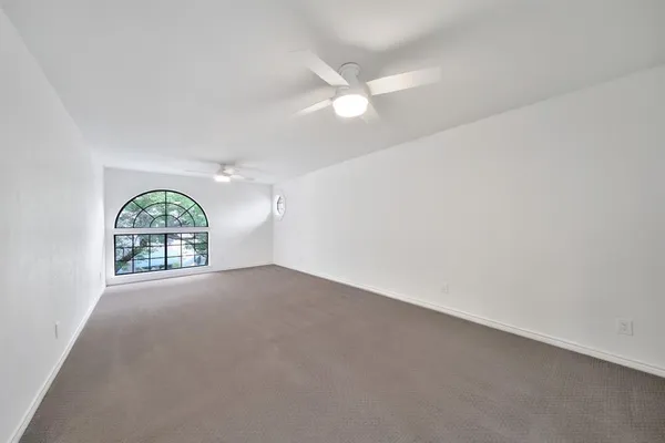 an empty room with windows and chandelier fan