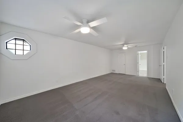 an empty room with a ceiling fan and a window