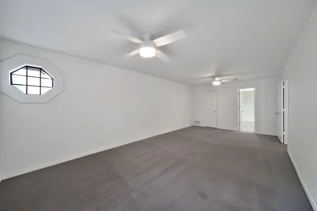 an empty room with a ceiling fan and a window
