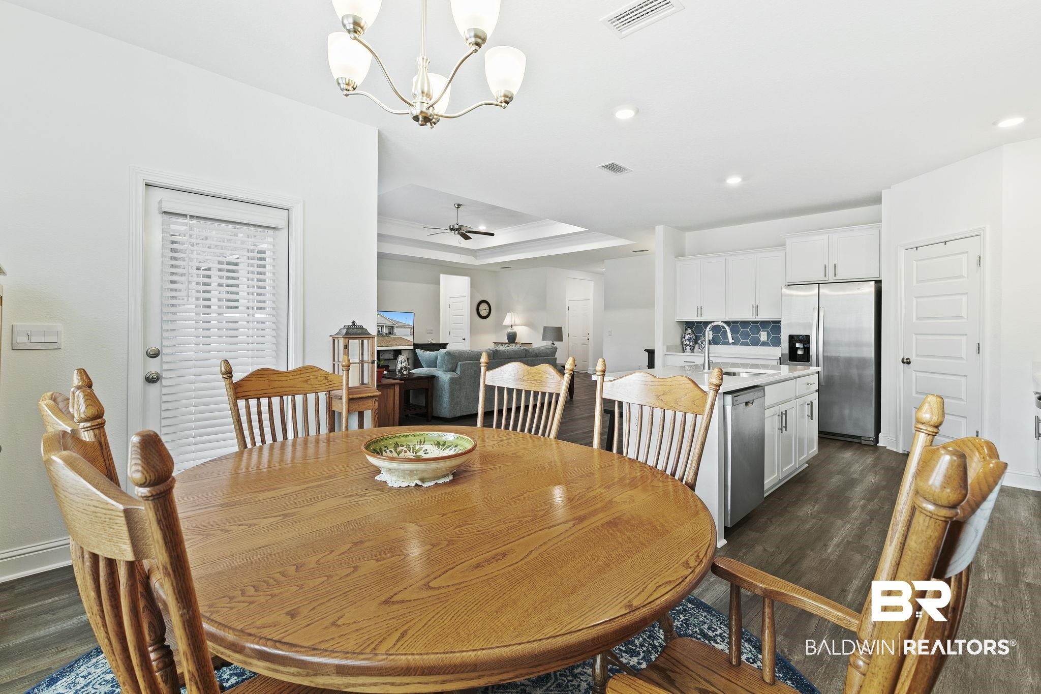 1141 Pencarro Boulevard Foley, AL 36535 - Photo 27 of 70 Dining room featuring ceiling fan with notable chandelier, a tray ceiling, dark hardwood / wood-style flooring, and sink