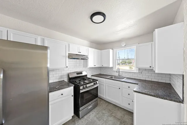 a kitchen with stainless steel appliances a sink cabinets and a window