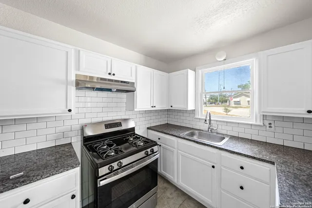 a kitchen with granite countertop white cabinets and appliances