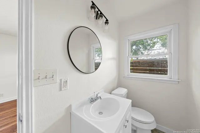 a bathroom with a sink a mirror a toilet and a window