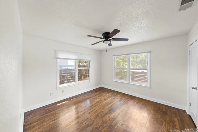 a view of an empty room with a window and wooden floor