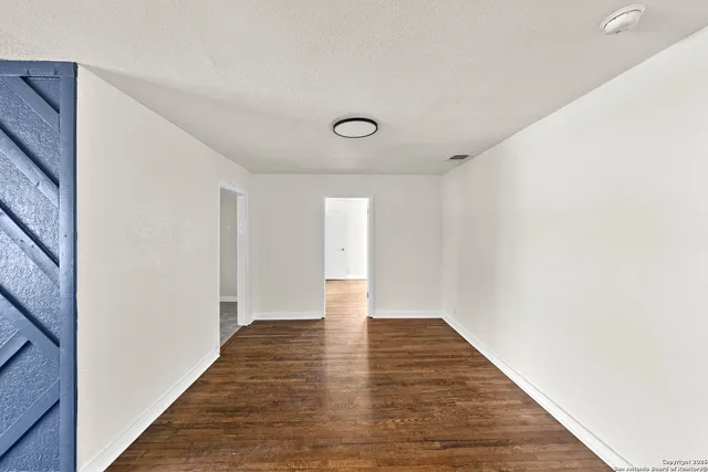 a view of an empty room with wooden floor