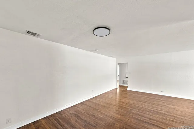 a view of a room with wooden floor and white walls
