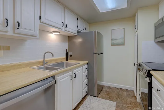 a kitchen with stainless steel appliances a sink a refrigerator and cabinets