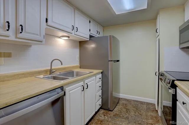a kitchen with stainless steel appliances granite countertop a sink a refrigerator and a stove