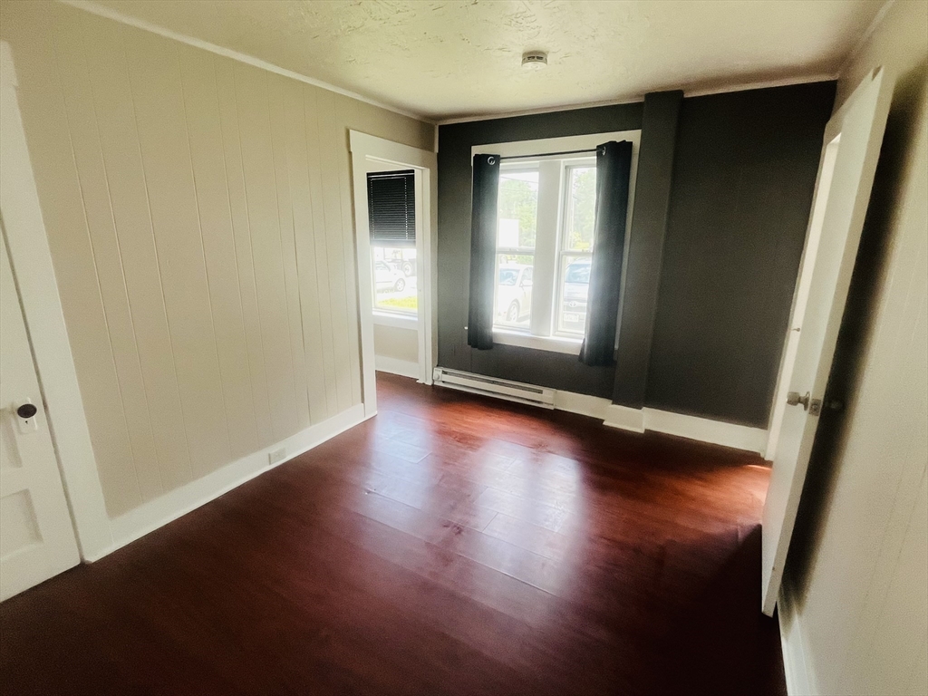 347 Main Street, Unit 2 Douglas, MA 01516 - Photo 4 of 5 an empty room with wooden floor and windows with curtains