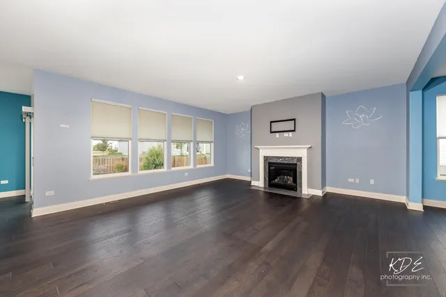 a view of an empty room with wooden floor fireplace and a window