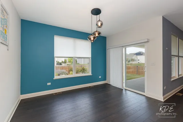 an empty room with wooden floor chandelier fan and windows