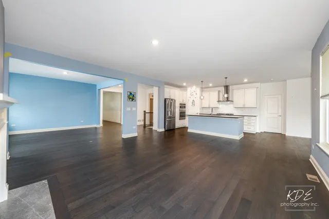 a view of a kitchen with a fridge and wooden floor