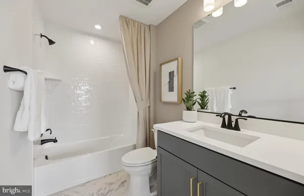 a bathroom with a sink a toilet a mirror a bathtub and shower