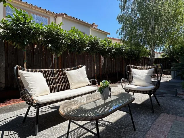 a view of a chairs and table in the back yard of a house