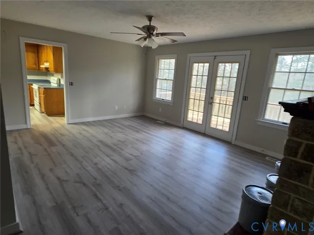 a view of an empty room with window and wooden floor