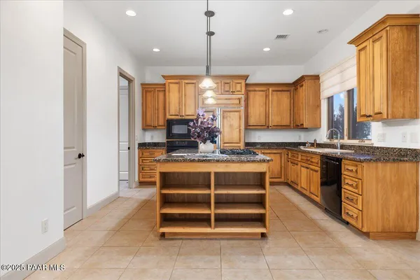 a kitchen with kitchen island granite countertop a stove a sink and a refrigerator