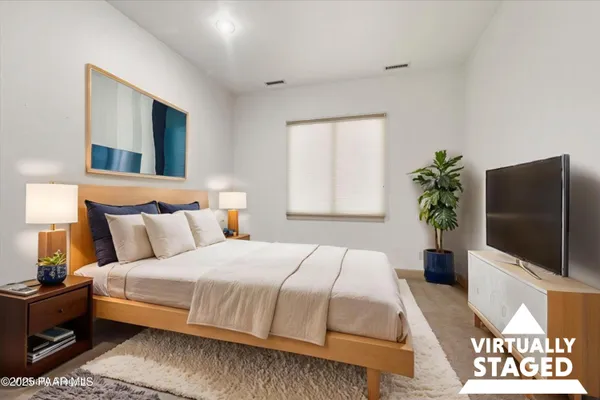 a bedroom with a large bed and a flat tv screen on dresser