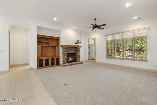 an empty room with windows fireplace and a ceiling fan