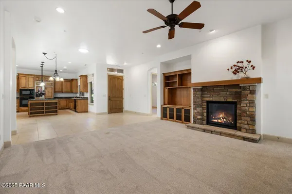 a view of a livingroom with a fireplace a ceiling fan a fireplace and a window
