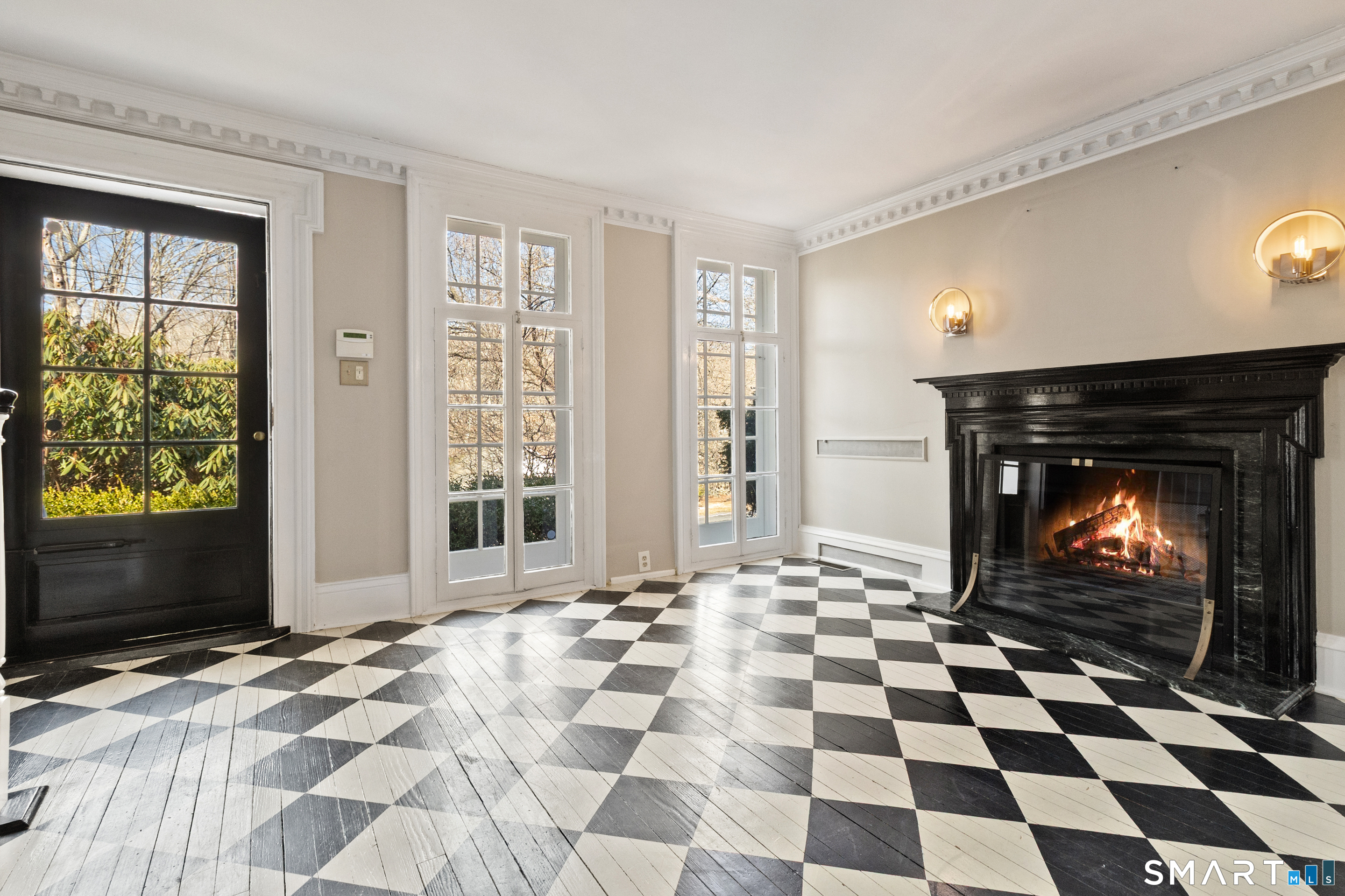 145 Lyons Plain Road Weston, CT 06883 - Photo 6 of 33 a living room with a black white checkered floor with a fireplace and a flat screen tv