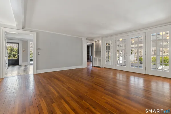 a view of an empty room with wooden floor fireplace and a window