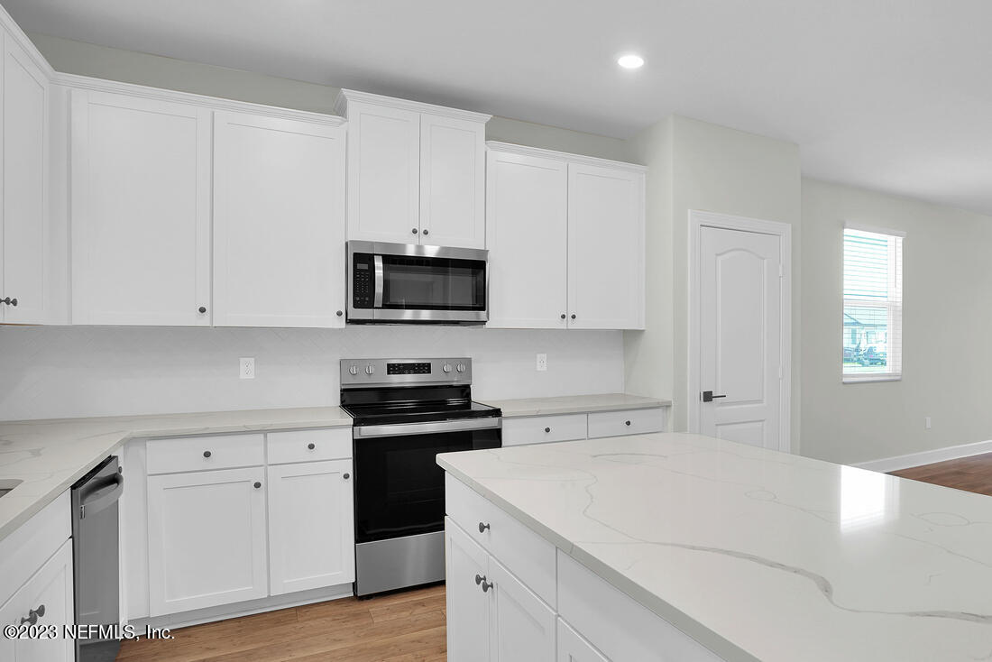 1074 Morgans Treasure Road St. Augustine, FL 32084 - Photo 3 of 11 a kitchen with white cabinets and black appliances