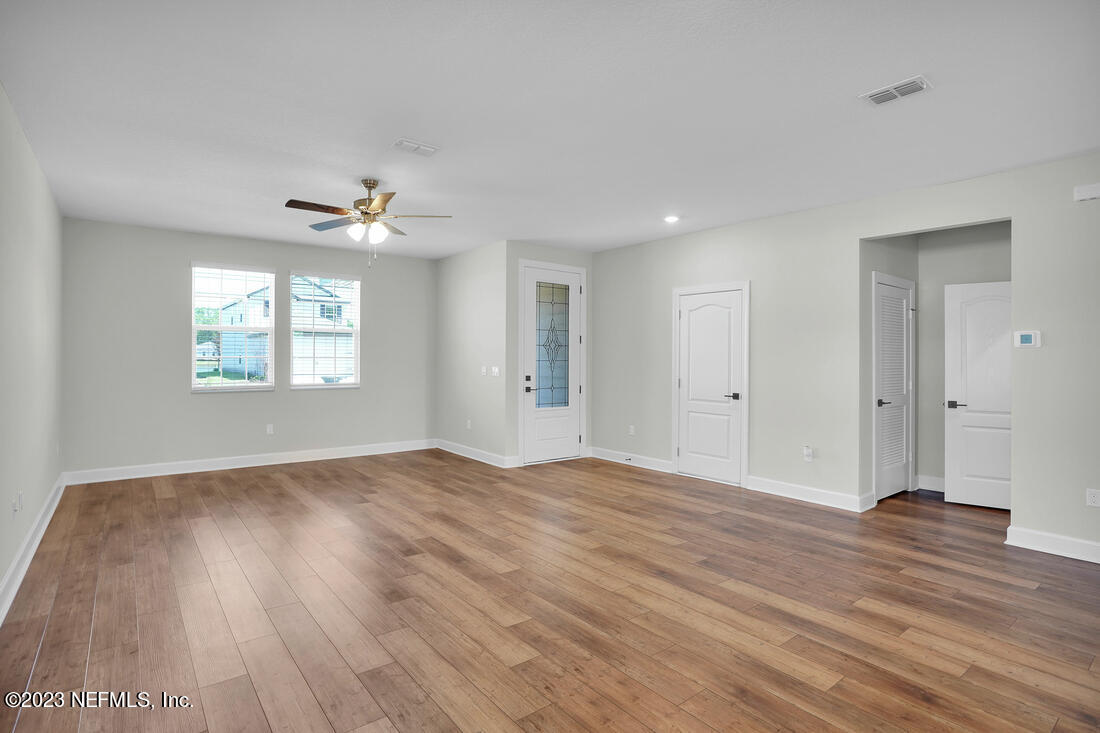 1074 Morgans Treasure Road St. Augustine, FL 32084 - Photo 5 of 11 an empty room with wooden floor chandelier fan and windows