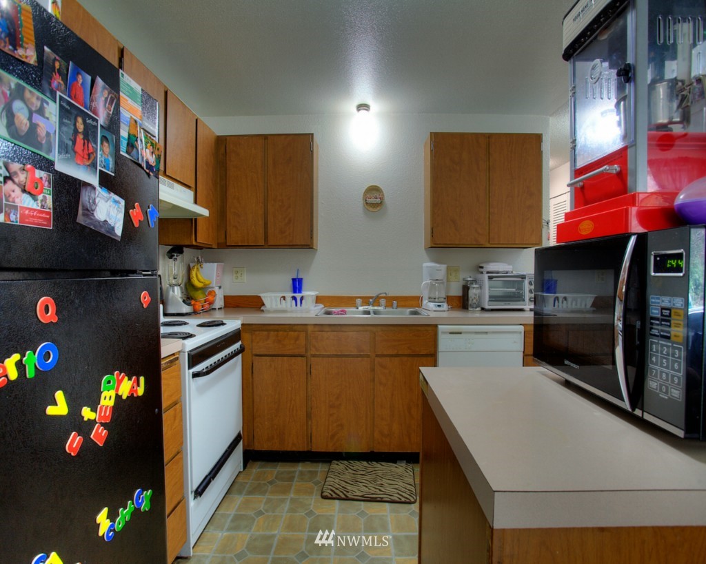 3919 Mason Loop Road Tacoma, WA 98409 - Photo 11 of 20 a kitchen with stainless steel appliances granite countertop a stove a sink dishwasher and a microwave