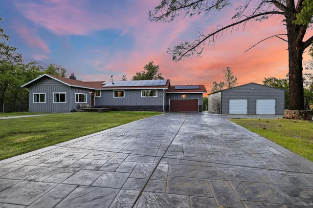 a view of a house with a yard and large tree