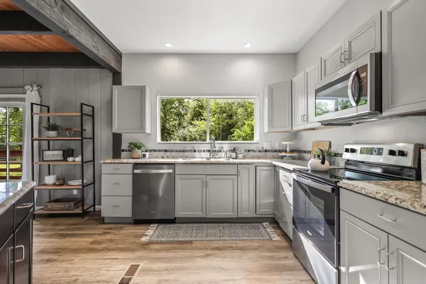 a kitchen with stainless steel appliances granite countertop a dining table chairs refrigerator and cabinets