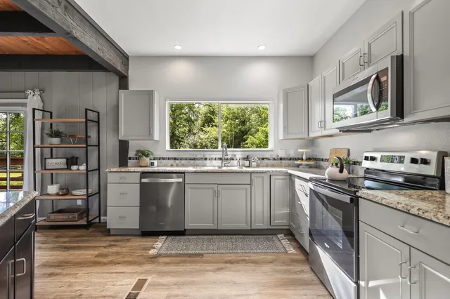 a kitchen with stainless steel appliances granite countertop a dining table chairs refrigerator and cabinets