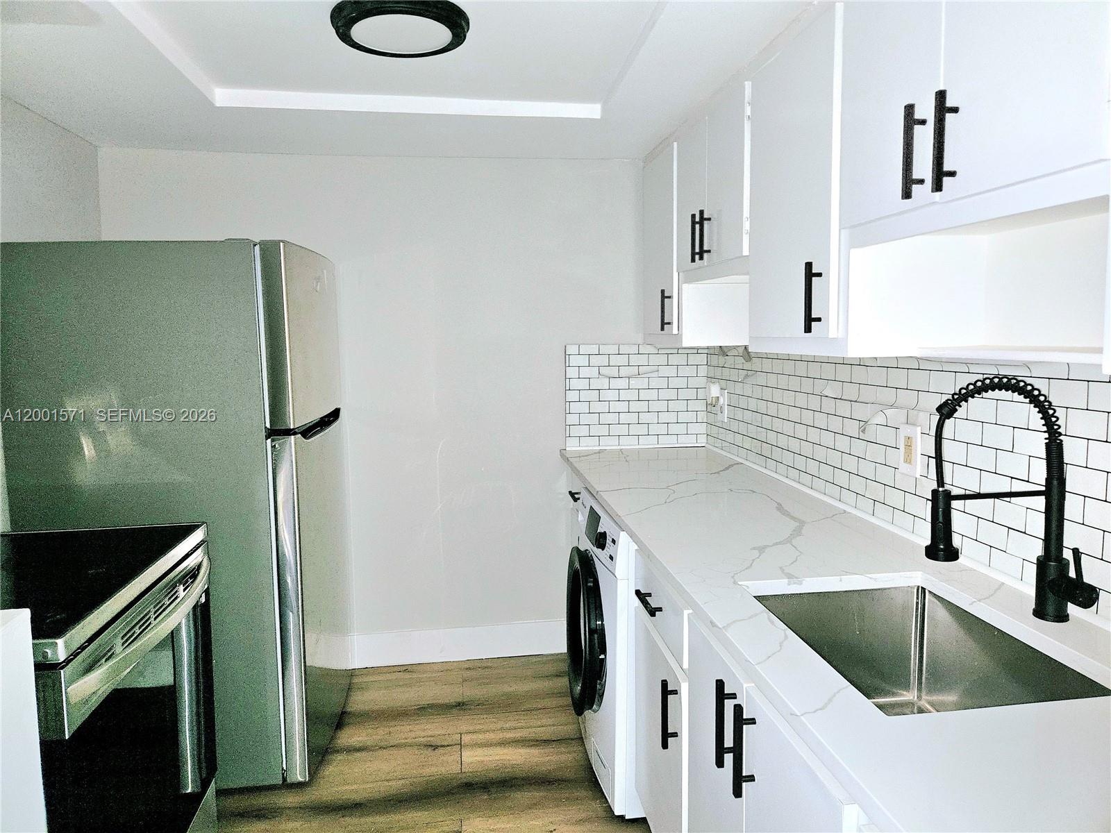 335 Southwest 20th Street, Unit 8 Fort Lauderdale, FL 33315 - Photo 4 of 11 a kitchen with stainless steel appliances granite countertop a sink stove and refrigerator