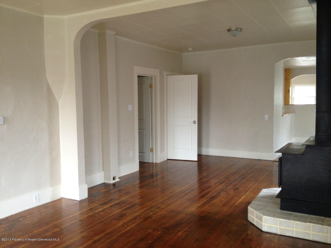 329 East 4th Street Rifle, CO 81650 - Photo 2 of 7 a view of an empty room with wooden floor and a window