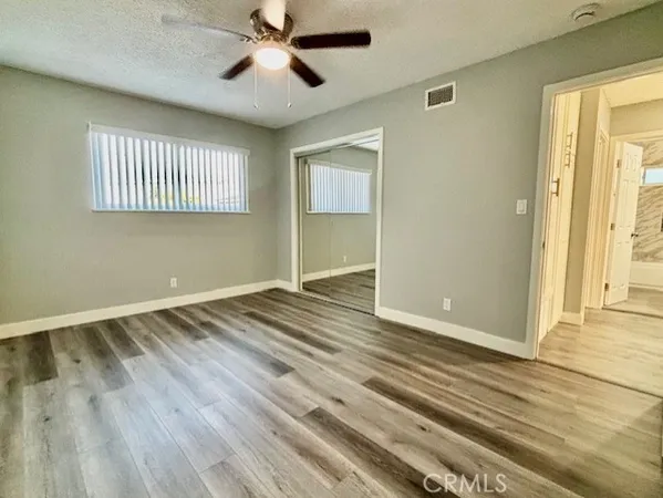 a view of empty room with wooden floor and fan
