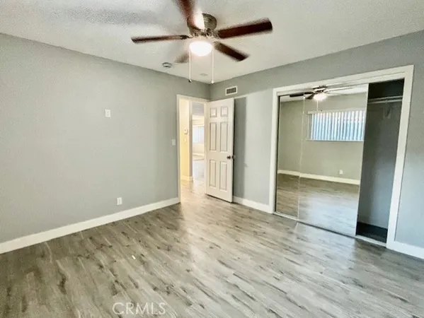 an empty room with wooden floor and a ceiling fan