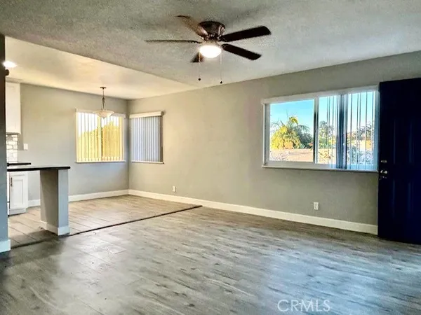 a view of an empty room with window and wooden floor