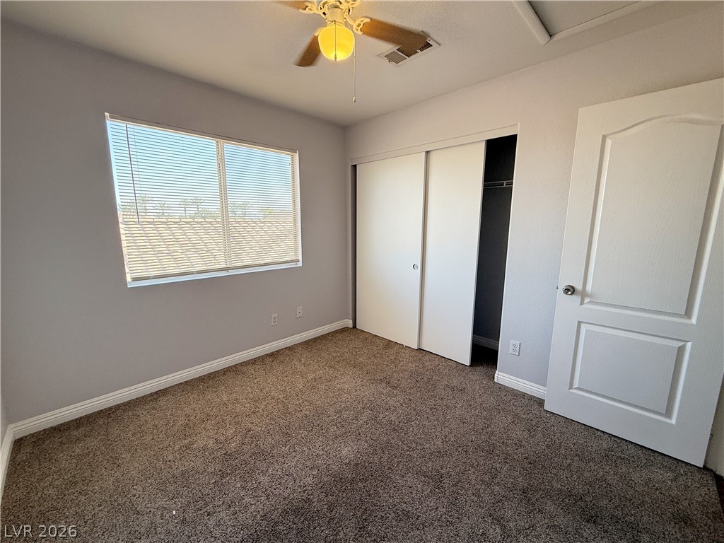 2185 Polynesia Circle Henderson, NV 89074 - Photo 28 of 37 A comfortable bedroom features plush carpeting, a wide window with horizontal blinds, and a practical closet with sliding doors.