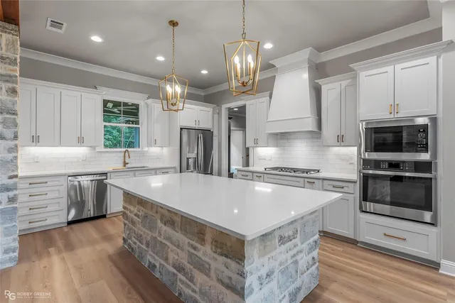 a large kitchen with stainless steel appliances granite countertop a stove a sink and a microwave