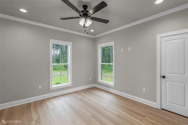 an empty room with wooden floor fan and windows