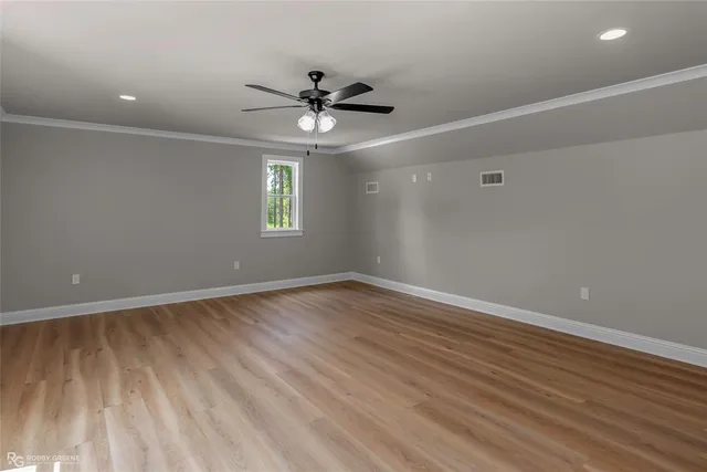 an empty room with wooden floor fan and windows