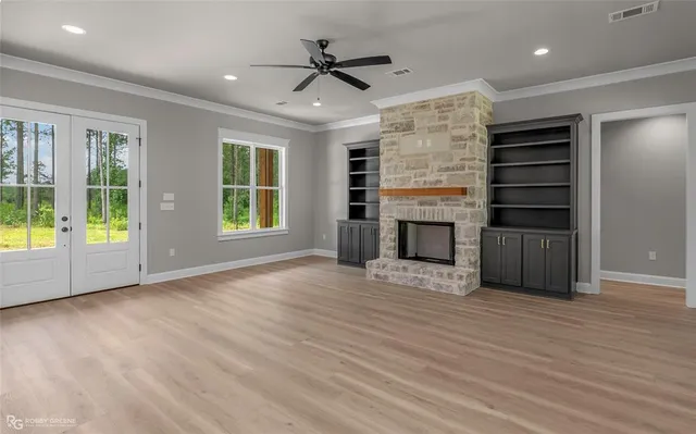 an empty room with wooden floor a ceiling fan and windows